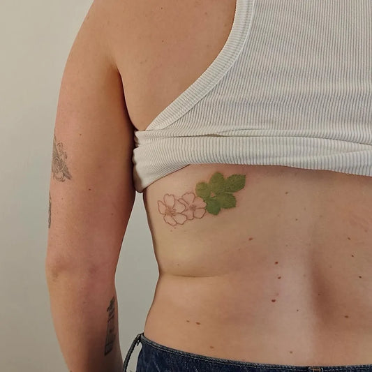 Small Stick and Poke Pink Cherry Blossoms and Green Maple Leaf Tattoo on Women Side by @clementineeyes