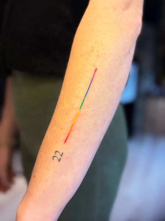 Small Stick and Poke Rainbow Line with 22 Tattoo on Women Arm by @thetattoobee