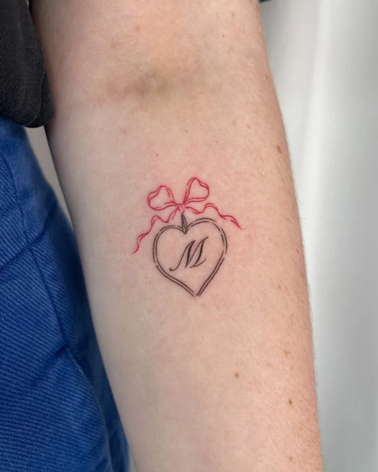 Small Stick and Poke Red Heart with Bow and M Letter Tattoo on Women Arm by @ellpokes