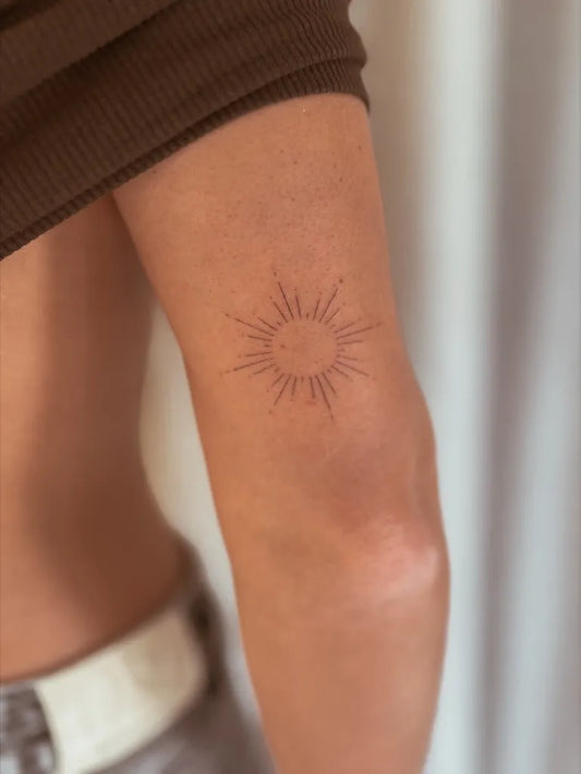 Small Stick and Poke Sun Tattoo on Women Upper Arm by @tara.pokes