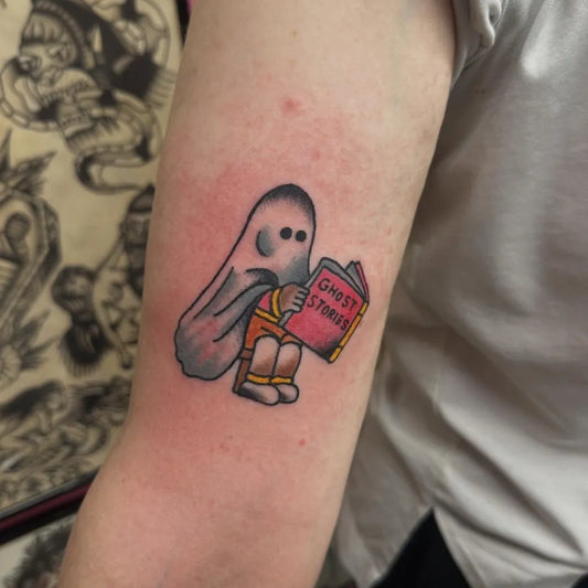 Small Traditional Ghost Reading Book Tattoo on Women Arm by @paulrestontattoo