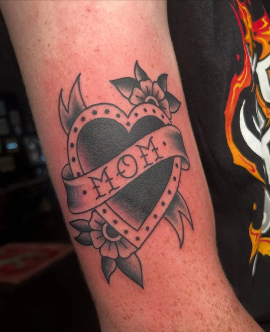 Small Traditional Heart with Mom Banner and Flowers Tattoo on Women Arm by @_tigerlilytattoos