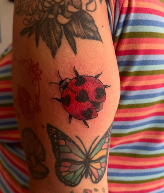 Small Traditional Ladybug Butterfly Tattoo on Women Arm by @vanitypunch