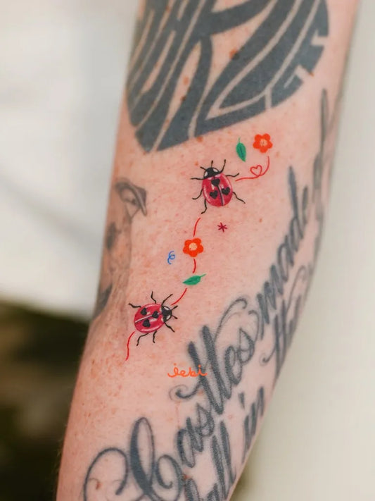 Small Traditional Ladybug Flowers Tattoo on Women Forearm by @jebi.tattoo