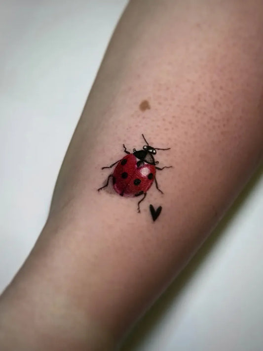 Small Traditional Ladybug Heart Tattoo on Women Arm by @saramtat