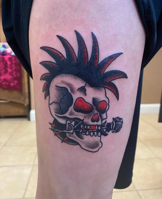 Small Traditional Skull with Mohawk and Microphone on Women Thigh Tattoo by @radiantenergytattoo
