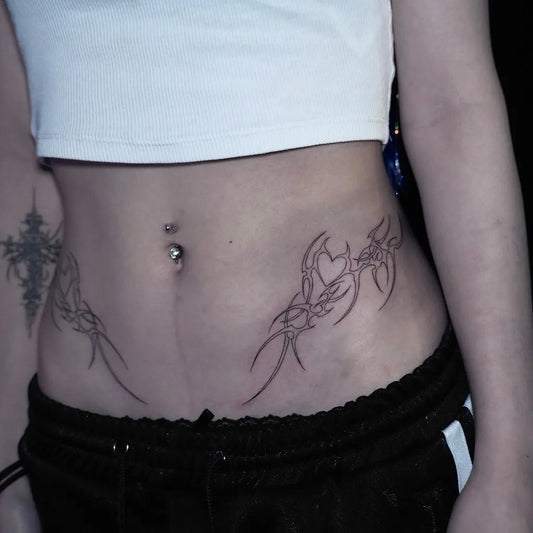 Small Tribal Heart Cross Wings on Women Stomach Tattoo by @zzigg_infelnaltattoo