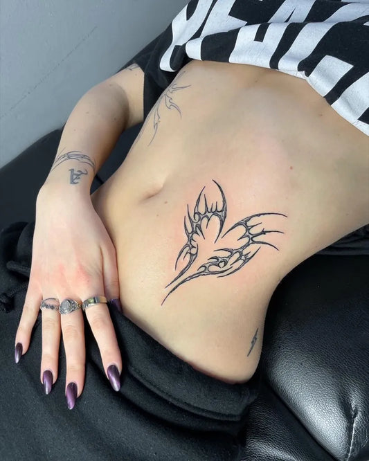 Small Tribal Wings Tattoo on Women Stomach by @armin.agne