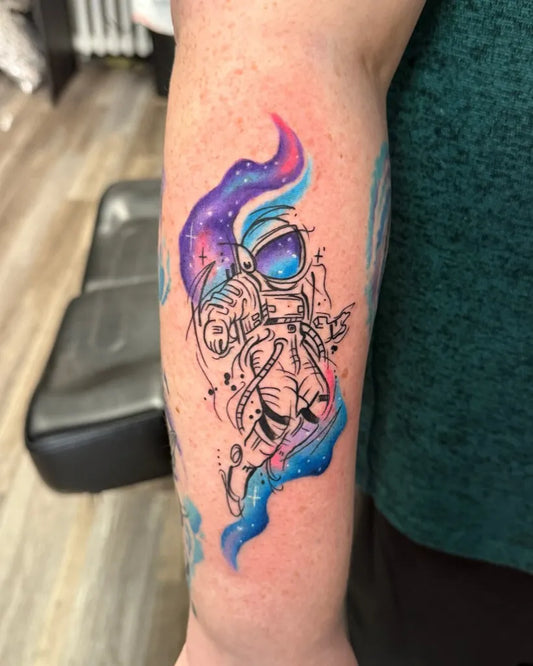 Small Watercolor Astronaut with Galaxy Swirls on Women Arm Tattoo by @9thgategallery