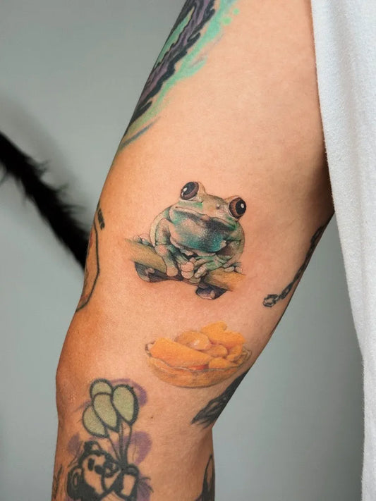 Small Watercolor Frog and Mango Tattoo on Women Arm by @lunayflorestattoo