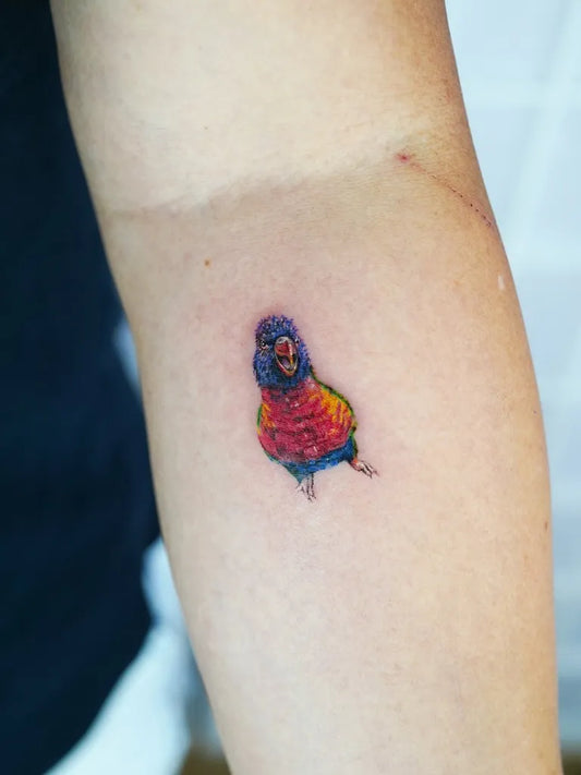 Small Watercolor Parrot Bird Tattoo on Women Arm by @tattoobyjinnie