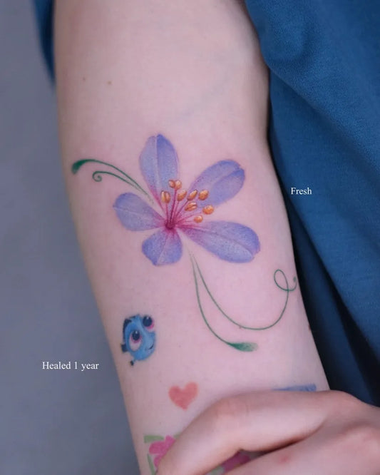 Small Watercolor Purple Hibiscus Flower with Fish and Heart on Women Arm Flower Tattoo by @kikimorryy