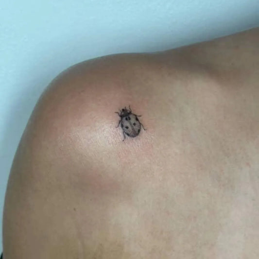 Tiny Black and Grey Ladybug Tattoo on Women Shoulder by @steeletanks