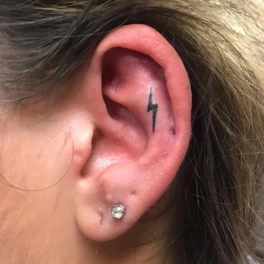 Tiny Black and Grey Lightning Bolt Tattoo on Women Ear by @sootattoos