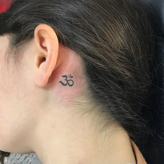 Tiny Black and Grey Om Symbol Tattoo on Women Behind the Ear by @shawn_mahaffey_tattoos