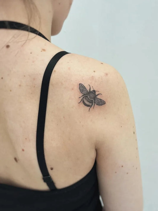 Tiny Blackwork Bee on Women Shoulder Tattoo by @clairedaisytattoos