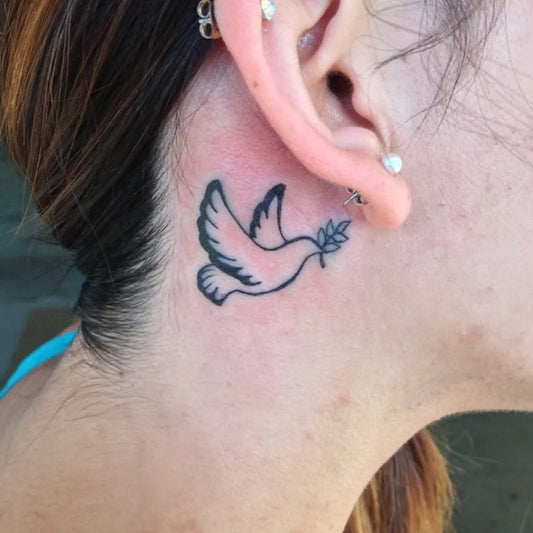 Tiny Blackwork Dove with Olive Branch Tattoo on Women Behind the Ear by @carlosmurillotattoos