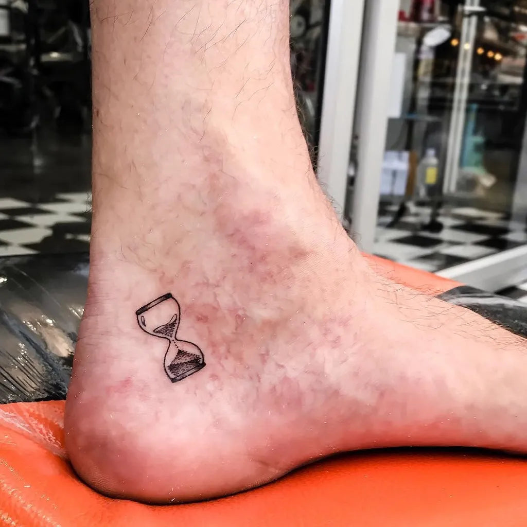 Tiny Blackwork Hourglass Tattoo on Men Ankle by @tos_tattoo