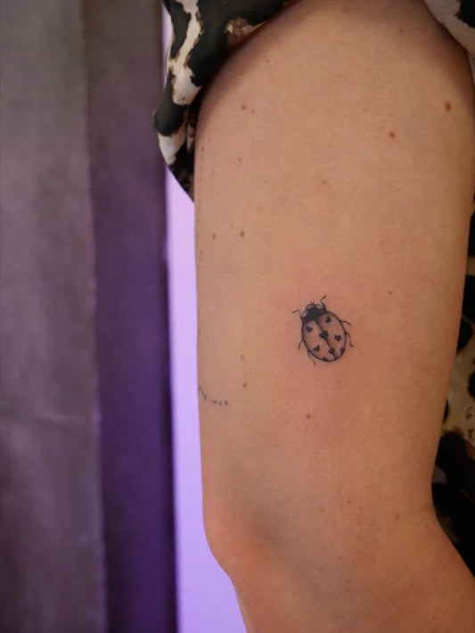 Tiny Blackwork Ladybug Tattoo on Women Arm by @titelune_tattoo