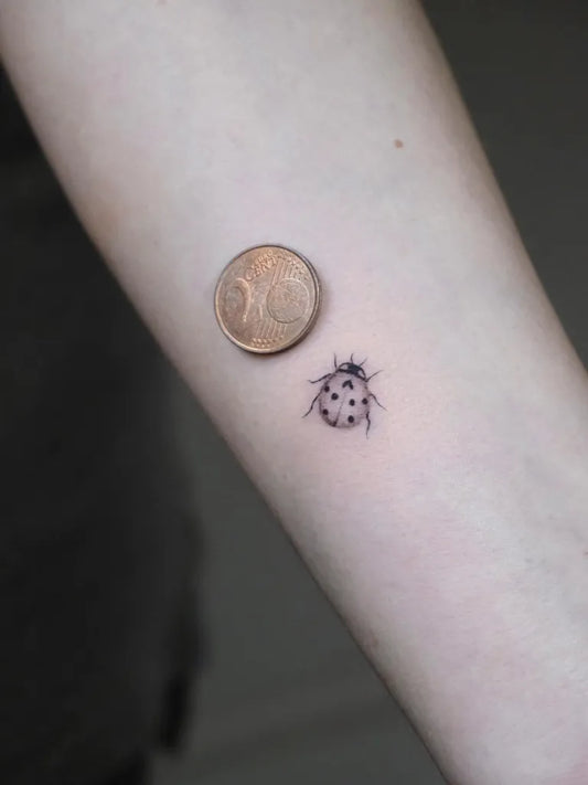 Tiny Blackwork Ladybug Tattoo on Women Arm by @vivida.tattoostudio