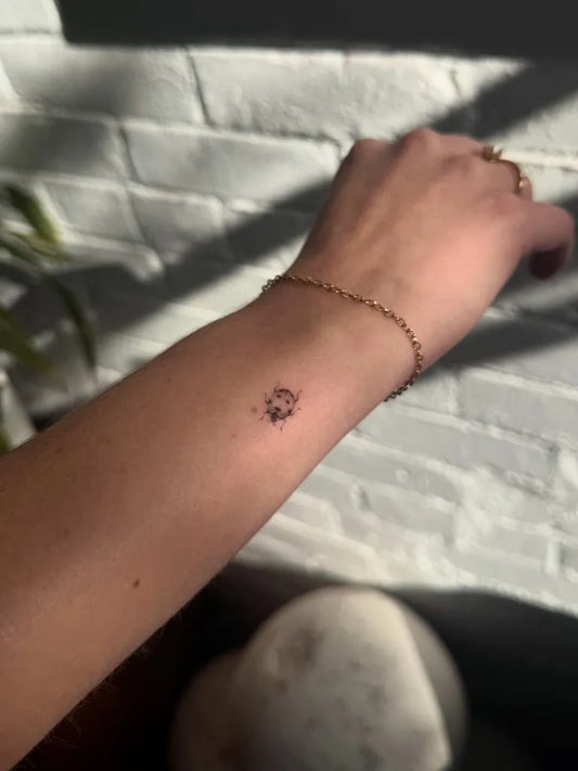 Tiny Blackwork Ladybug Tattoo on Women Wrist by @zuzu.tattoos