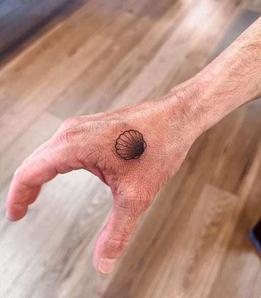 Tiny Blackwork Scallop Shell Spiritual Tattoo on Men Hand by @sarahpeteh