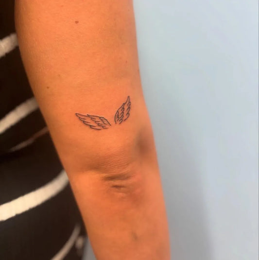 Tiny Fine Line Angel Wings Tattoo on Women Arm by @amieelizabeth_tattoos