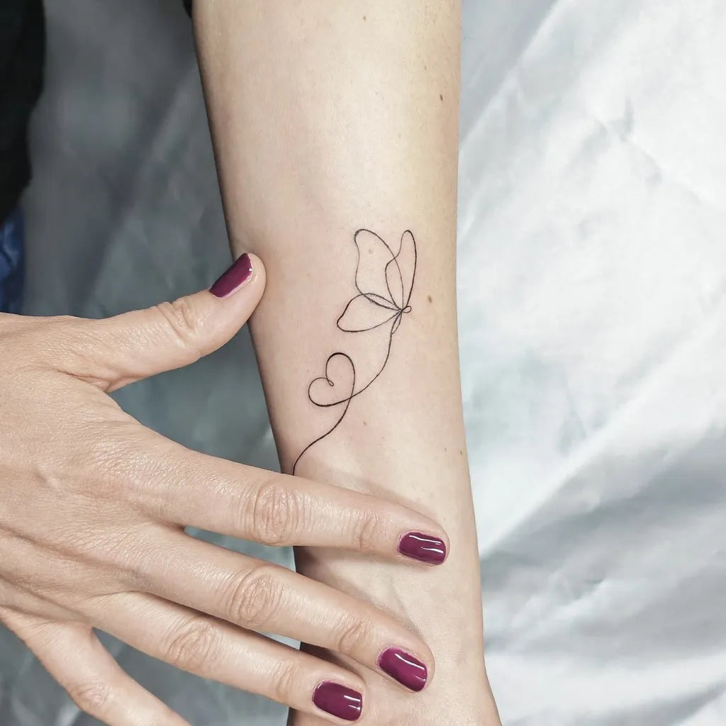 Tiny Fine Line Butterfly Heart Stem on Women Arm Tattoo by @lia.cerullo