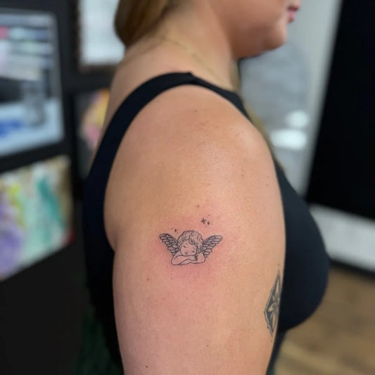 Tiny Fine Line Cherub Tattoo on Women Shoulder by @the.asylum.ink