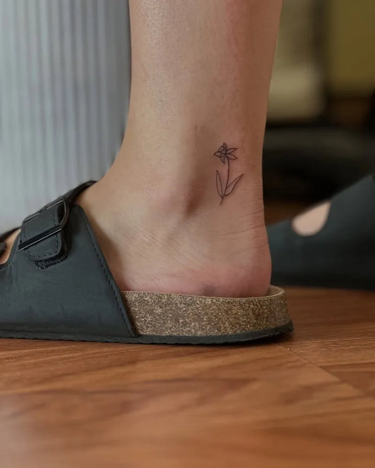 Tiny Fine Line Daffodil Tattoo on Women Ankle by @keeley.tattoo