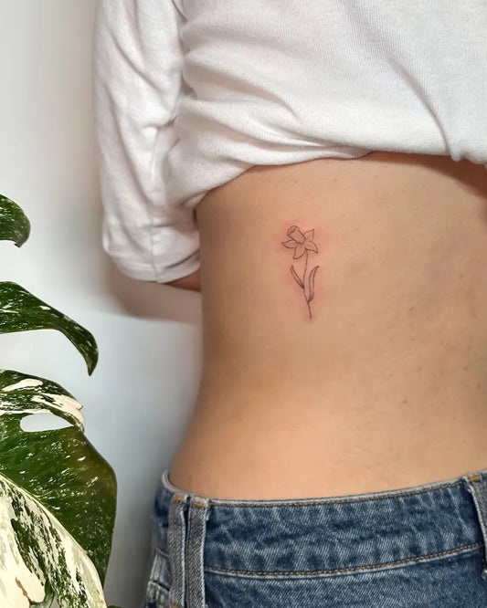 Tiny Fine Line Daffodil Tattoo on Women Side by @daisy.pokes