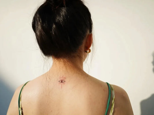 Tiny Fine Line Evil Eye on Women Back Tattoo by @lucidella.art.spirit