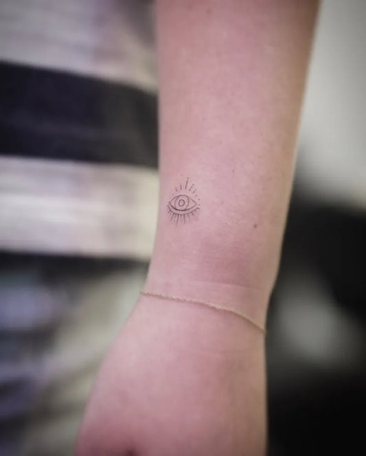 Tiny Fine Line Evil Eye on Women Wrist Tattoo by @ellie_s.tattoo