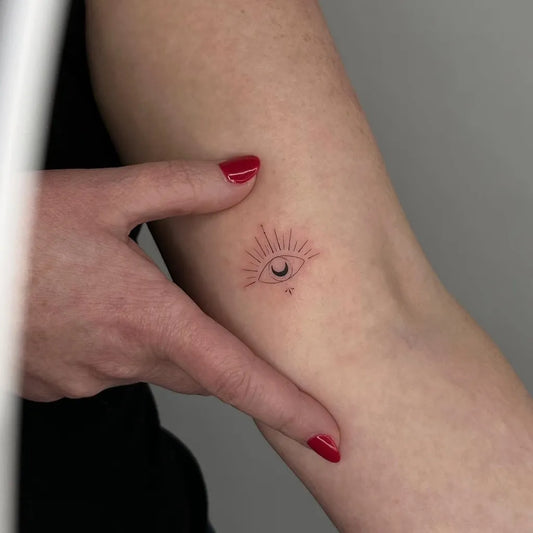 Tiny Fine Line Evil Eye with Sun and Crescent on Women Arm Tattoo by @mrspiotattoo