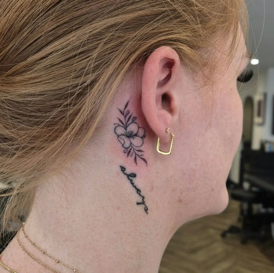 Tiny Fine Line Flower and Always Tattoo on Women Behind the Ear by @kellybrowntattoos