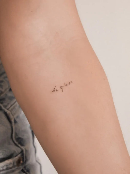 Tiny Fine Line French Phrase on Women Upper Arm Tattoo by @hugoyrla.ink