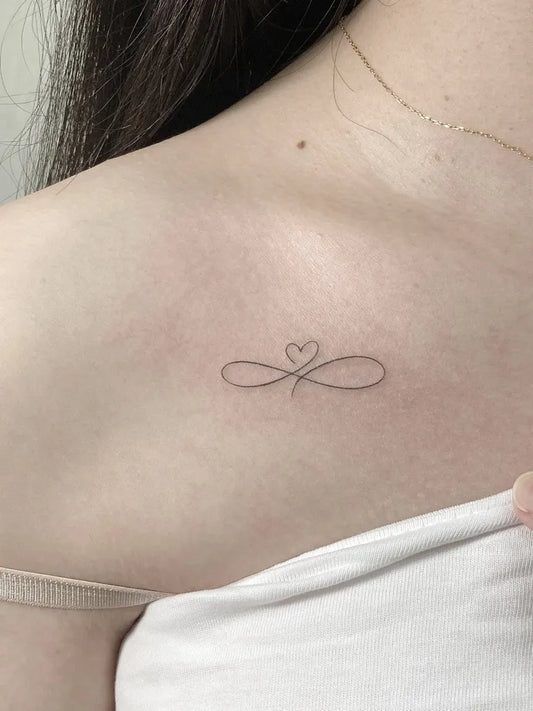Tiny Fine Line Infinity Heart Tattoo on Women Shoulder by @playground_tat2