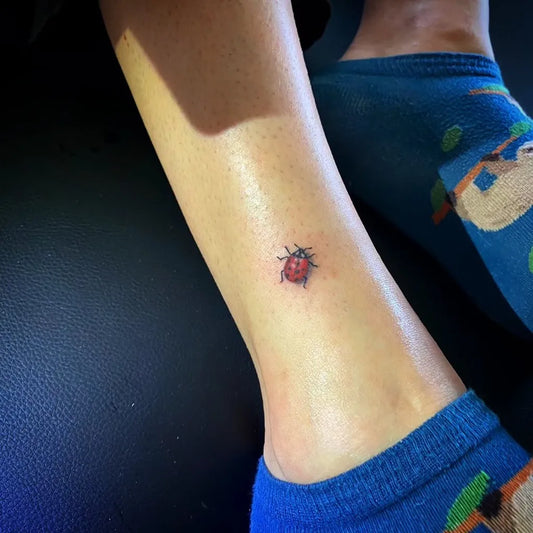 Tiny Fine Line Ladybug Tattoo on Women Ankle by @maya.tattoo.artist