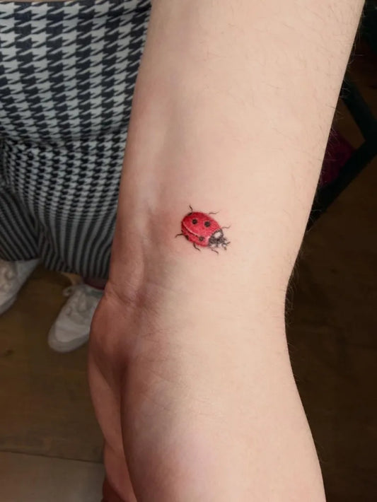 Tiny Fine Line Ladybug Tattoo on Women Arm by @yudari.ink