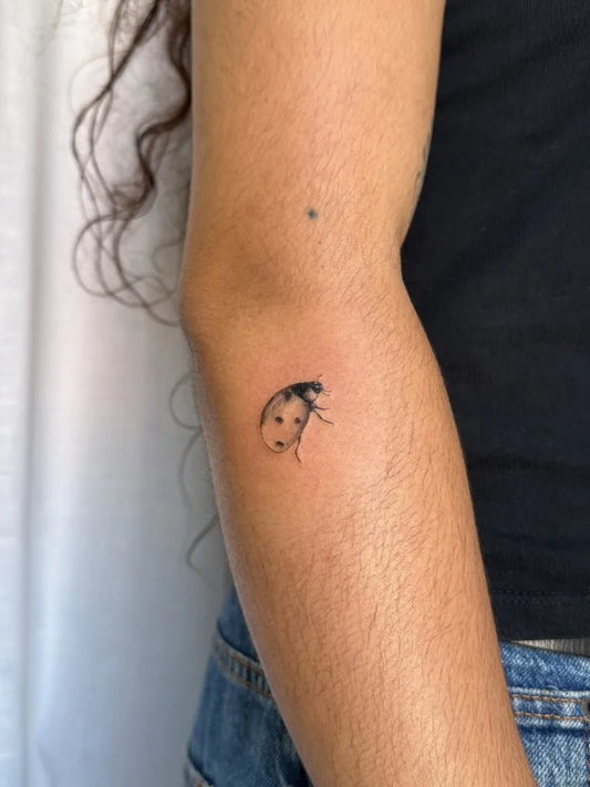 Tiny Fine Line Ladybug Tattoo on Women Arm by @zalitattoos