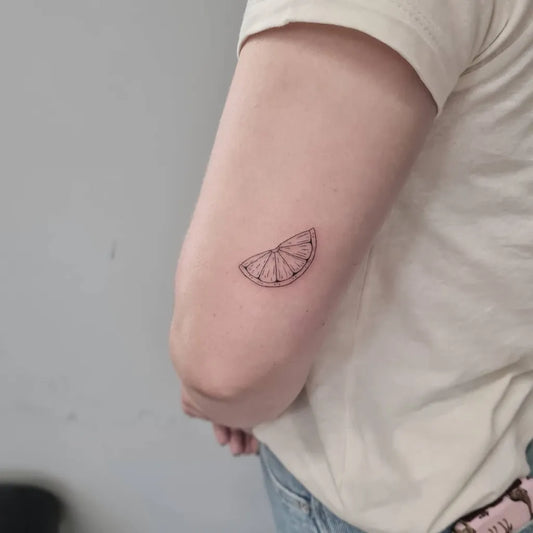 Tiny Fine Line Lemon Slice on Women Upper Arm Tattoo by @leigh.tattoo