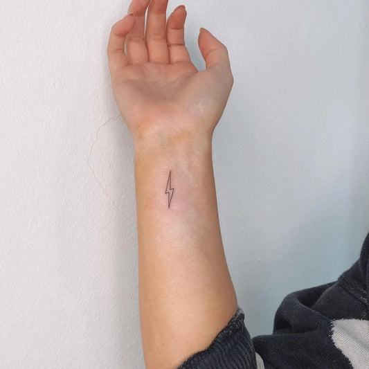 Tiny Fine Line Lightning Bolt Tattoo on Women Wrist by @pollytatttoo