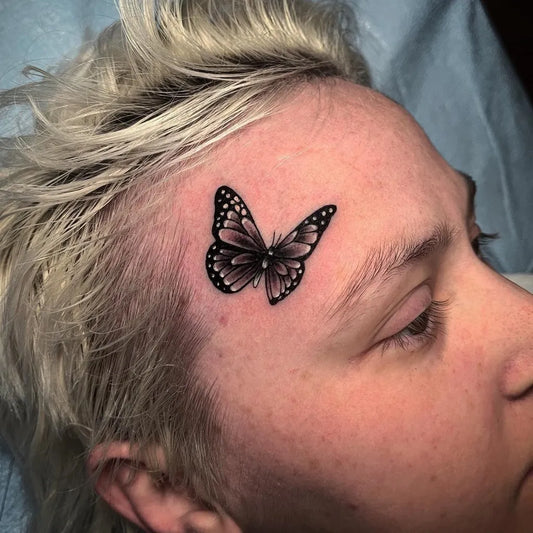 Tiny Fine Line Monarch Butterfly on Women Face Tattoo by @trailer_mullet