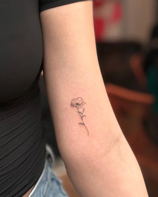 Tiny Fine Line Poppy Flower with Stem on Women Upper Arm Tattoo by @haute.homeless
