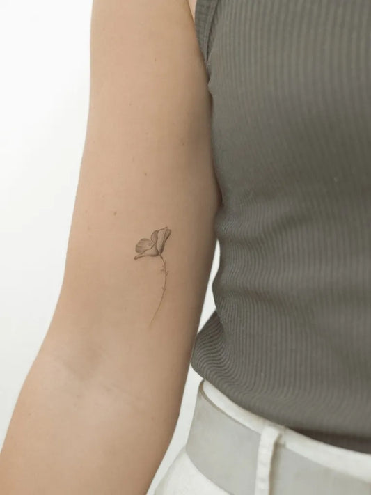 Tiny Fine Line Poppy Tattoo on Women Arm by @vadelma.tattoo.amsterdam