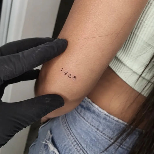 Tiny Fine Line Roman Numerals Tattoo on Women Arm by @alexherndzstudio