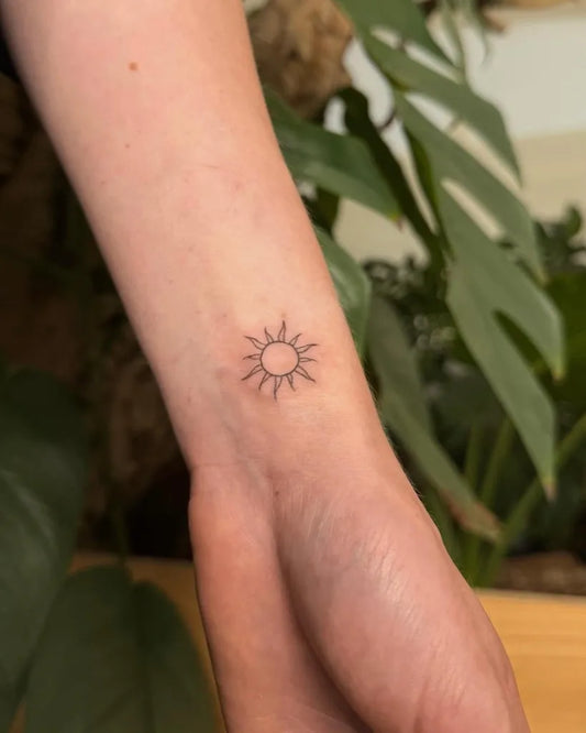 Tiny Fine Line Sun on Women Wrist Tattoo by @brazz.tattoo.art