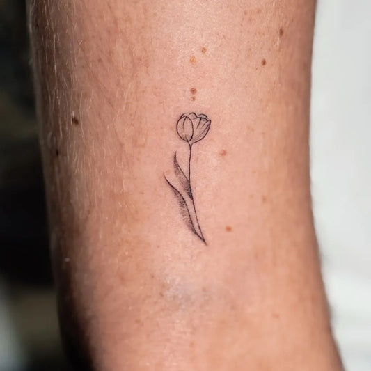 Tiny Fine Line Tulip Tattoo on Women Arm by @elizatattooamsterdam
