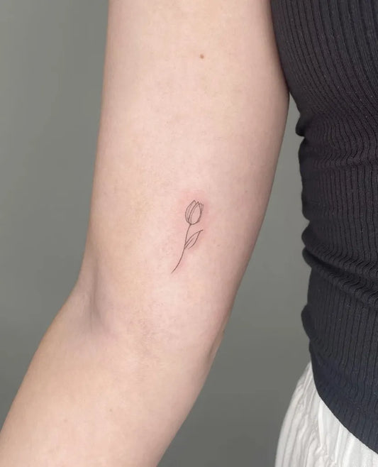 Tiny Fine Line Tulip Tattoo on Women Arm by @mudi.ink