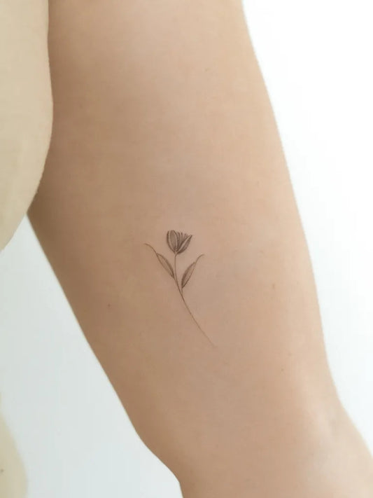Tiny Fine Line Tulip Tattoo on Women Arm by @vadelma.tattoo.amsterdam